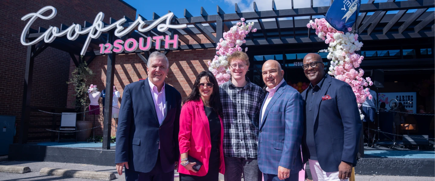 Five people in front of Coopers 12 SOUTH restaurant with pink cherry blossom decor in Nashville.