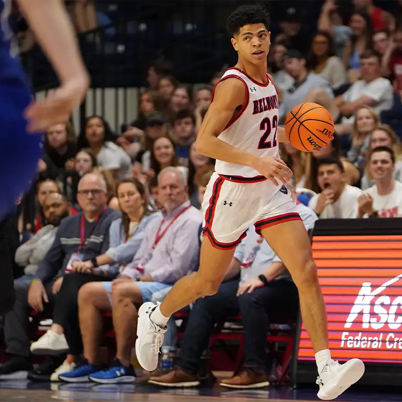 An indoor picture of a Belmont male basketball player being guarded by another male basketball player on the basketball court