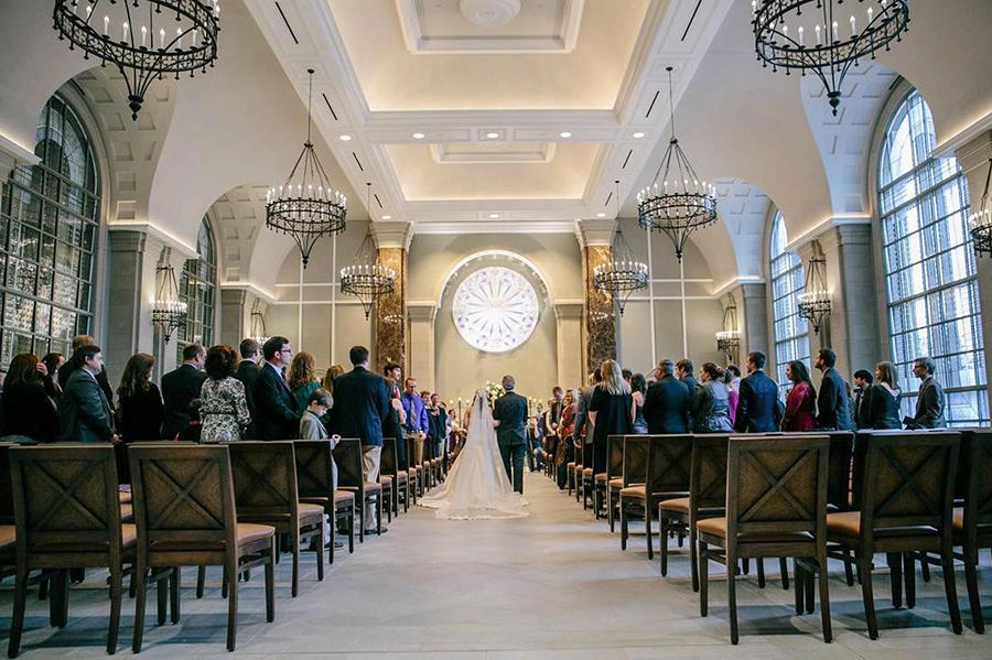 A photo of a beautiful wedding ceremony taken from down the aisle looking at the bride and groom