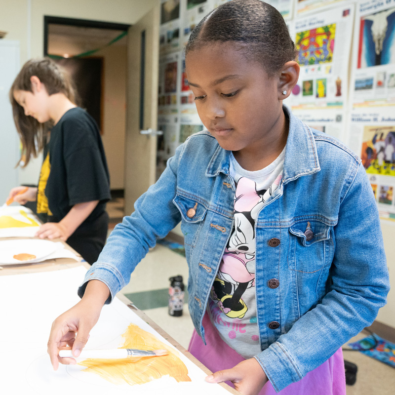 Young girl painting a picture in a classroom