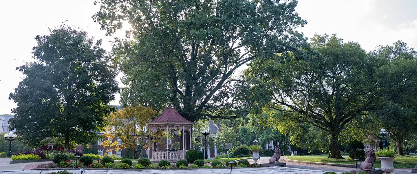 A decorative gazebo surrounded by lush greenery on the Belmont University campus, with a clear blue sky in the background.