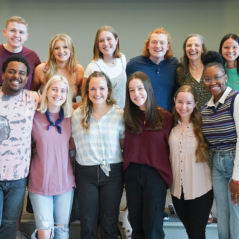 A group of students stands and poses in the chapel.