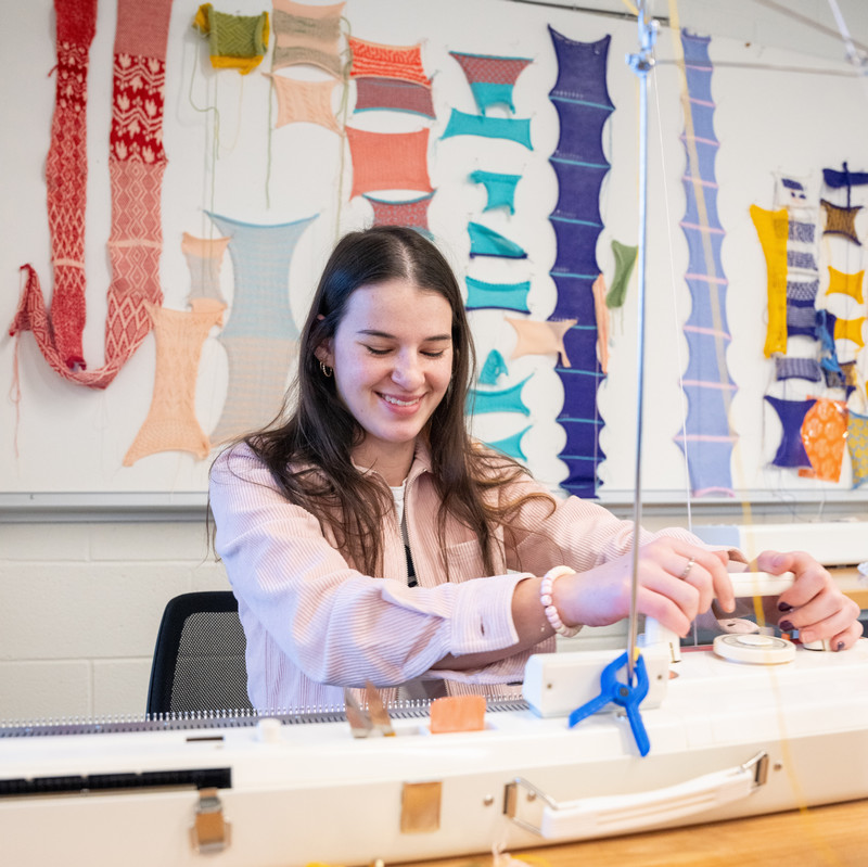 a person joyfully works the knitting machine