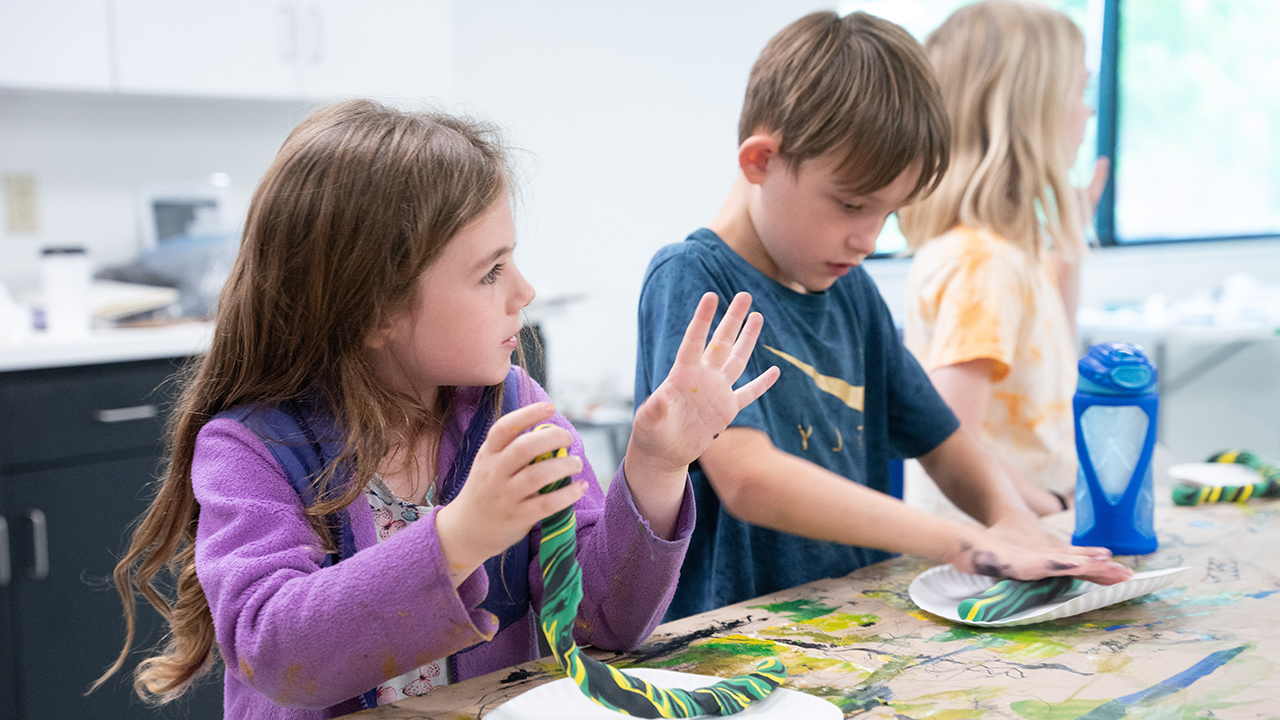 Kids rolling foam clay on a table