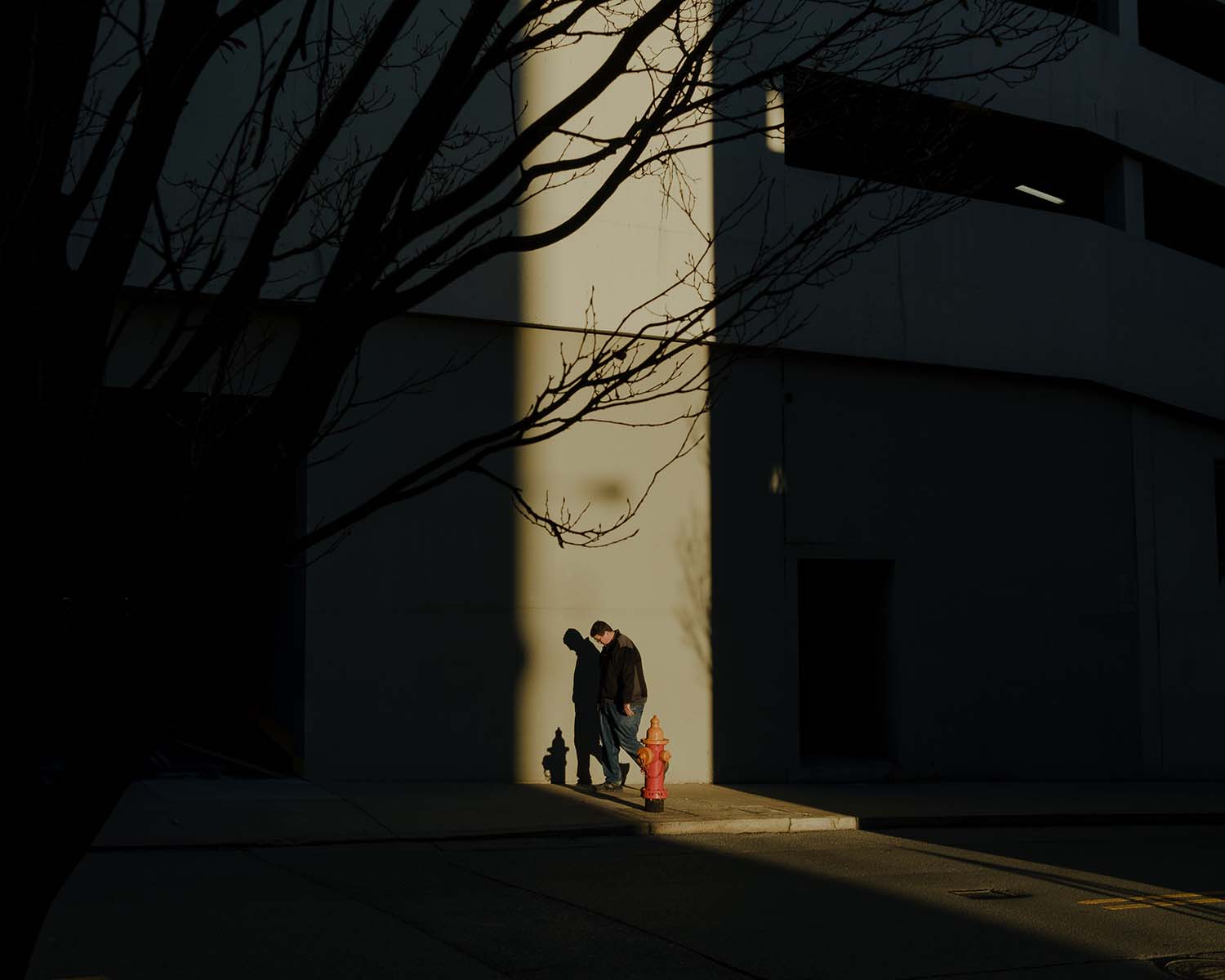 man walking on city street at sunset with light shining on him